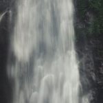 Water Clarity - Photo of Man Sitting Near Waterfalls