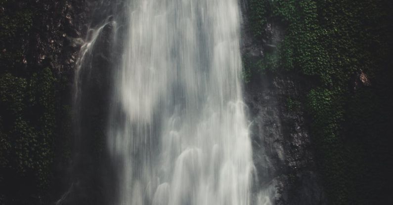 Water Clarity - Photo of Man Sitting Near Waterfalls